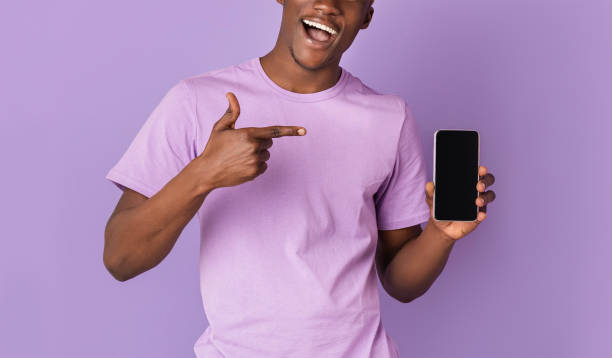 istock Unrecognizable black guy pointing at cellphone screen with black space for your app or website design, lilac background 1239261910