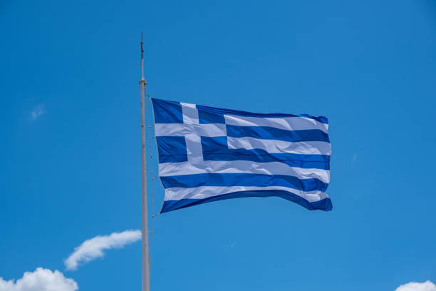 istock Greek flag waving against blue sky background 1239261968