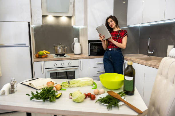 istock Young woman using a tablet computer to cook different vegetables in her kitchen for everything about healthy nutrition. 1239275405