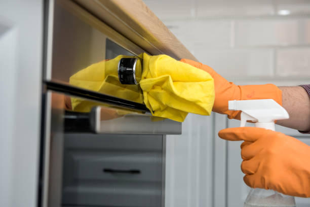 istock Man's hand in gloves cleaning the kitchen oven 1239297327