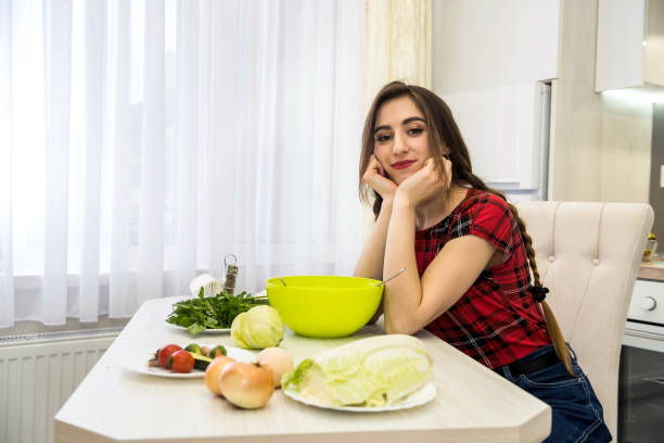 istock Girl posing at a kitchen table while prepares a salad of different vegetables and greens for a healthy lifestyle. 1239298966