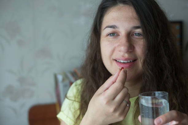 istock Woman is putting supplements in her mouth. 1239318889