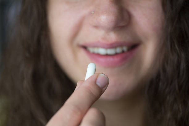 istock Woman is putting supplements in her mouth. 1239319407