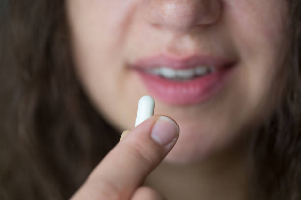 istock Woman is putting supplements in her mouth. 1239319422