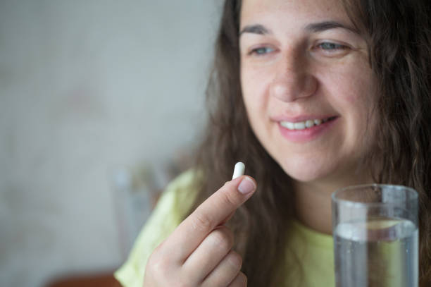istock Woman is putting supplements in her mouth. 1239319437