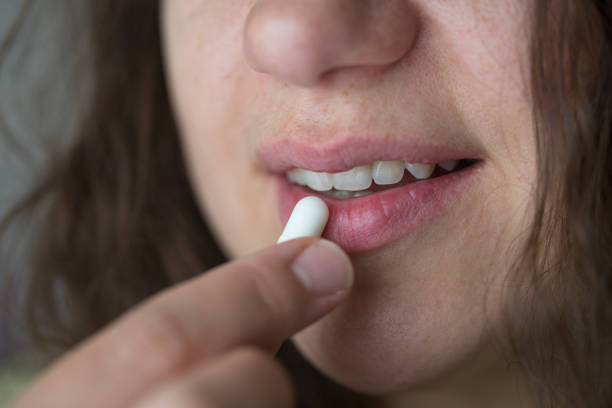 istock Woman is putting supplements in her mouth. 1239319956