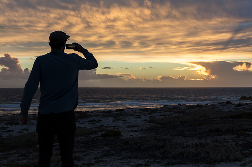 Young Man Taking Photos of Magnificent Sunset View
