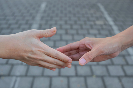 Close up shot of two millenials shaking hands in the street