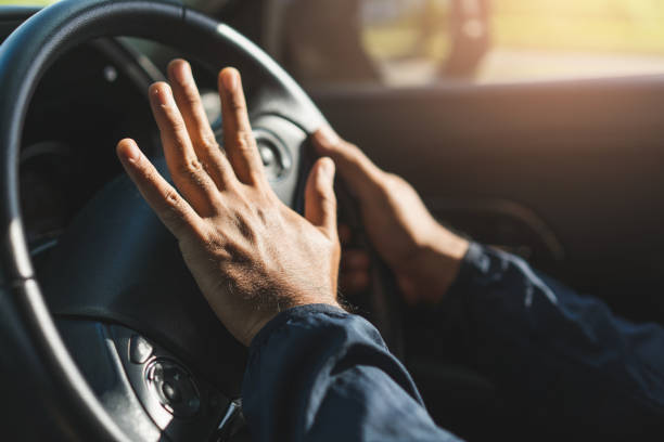 istock Hand man pushing car horn while driving car. 1239345376