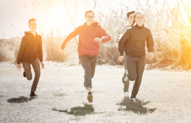 istock Cheerful teens running on green lawn 1239350182