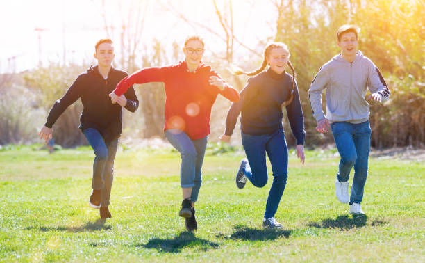 istock Cheerful teens running on green lawn 1239350186
