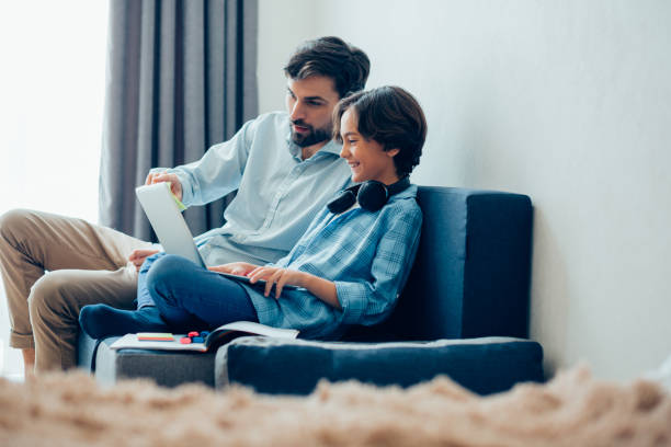 istock Mirthful boy with gadget sitting spending time with his parent 1239358144