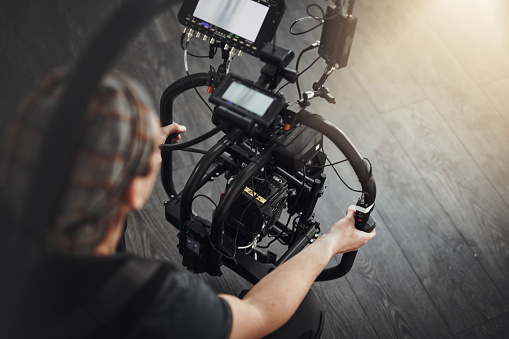 Close-up of operator using professional camera during shooting with director controlling the process