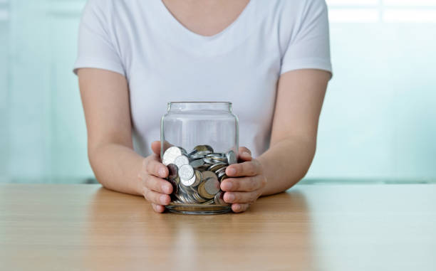 istock Woman holding glass jar with coins 1239368414