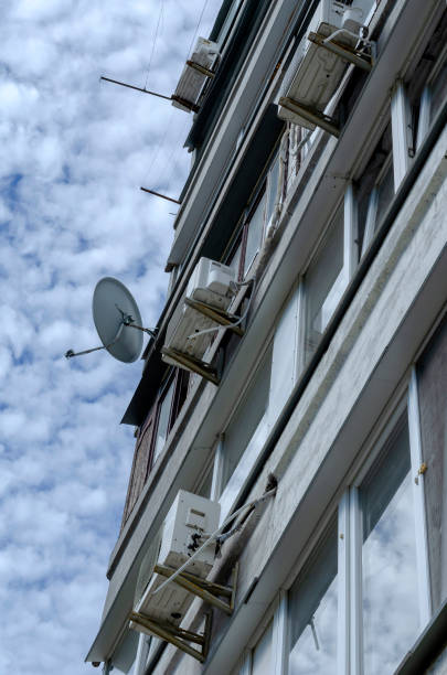 la façade d’appartements de plusieurs étages avec climatisation sur un fond de ciel nuageux. - television aerial flash photos et images de collection