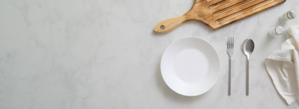 istock Marble dinning table with white plate, silverware, wooden tray and copy space 1239382946