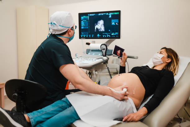 schwangere frau beobachtet ihr baby auf dem ultraschall - fetus stock-fotos und bilder