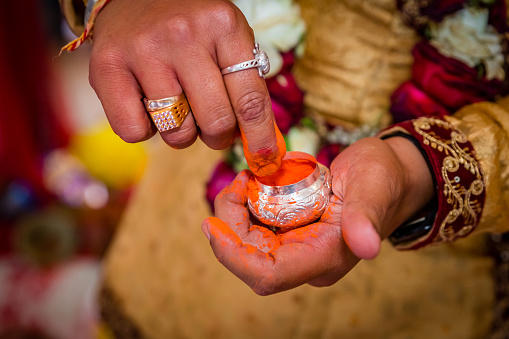 The Groom's hand holding sindur or Vermilion before applying on the bride`s hair-parting.