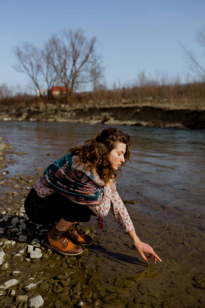 istock Woman scooping water of beautiful river 1239417718