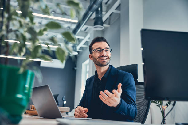 istock Smiling man gesticulating and sitting at table with laptop 1239434738