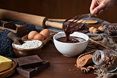 Woman hands making chocolate mousse and cookies on a wooden table in a rustic kitchen