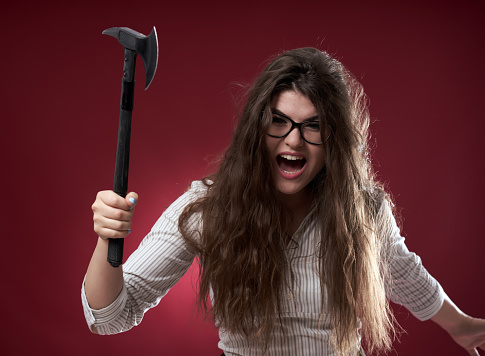 Enraged businesswoman wielding a hatchet ready to attack