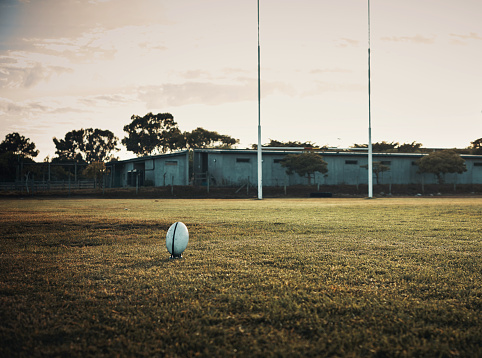 Still life shot of a rugby ball on an empty rugby field during the early hours of the morning at a sports club