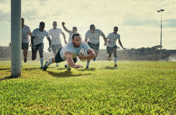 This is why he is called a great player Full length shot of a handsome young rugby player scoring a try while training on a rainy day rugby stock pictures, royalty-free photos & images