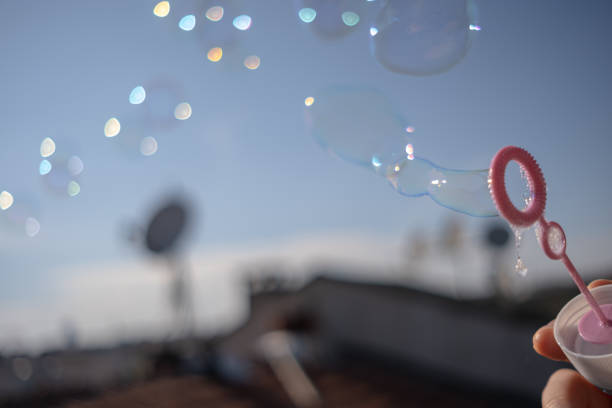 istock Young woman blowing soap bubbles on the roof 1239479068