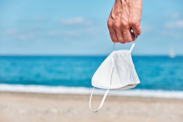 man with a face mask in his hand on the beach