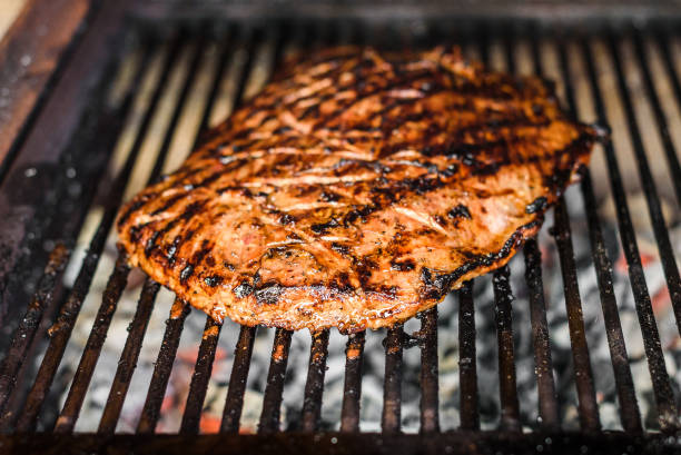 istock Grilling marinated angus beef flank steak on hot coals barbecue grill. 1239492504