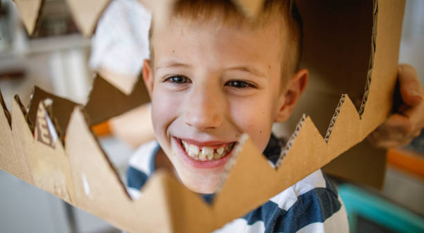 istock Smiling boy wearing a cardboard dinosaur costume 1239505859