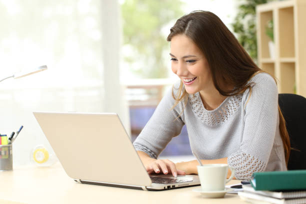 istock Happy student reading content on a laptop at home 1239512192