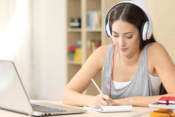 istock Student with headphones taking notes at home 1239514815