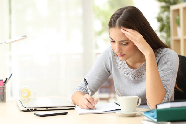 istock Concentrated woman writing on notebook at home 1239515872