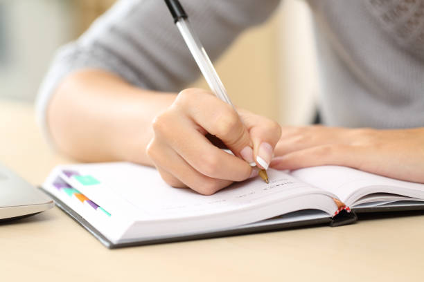 istock Woman hands writing notes on agenda on a desk 1239518028