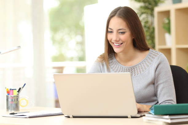 istock Happy student using laptop on a desk at home 1239520445