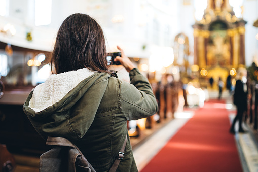 Young woman is photographing religious service in Saint Michael church, Hamburg.