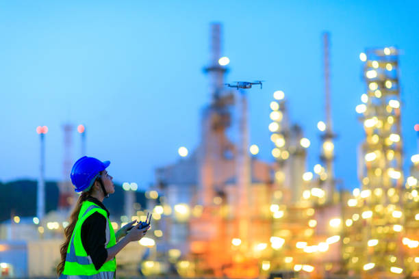 l'ingegnere donna che utilizza il drone per l'ispezione in alto nell'impianto di raffineria. - industrial district foto e immagini stock