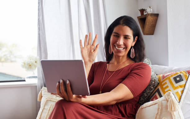 istock Woman smiling and waving during a video call on her tablet 1239531677
