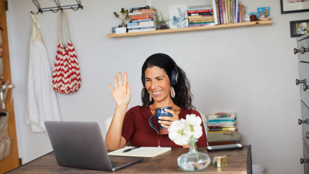 femme de sourire agitant pendant un chat vidéo sur un ordinateur portatif - connection usa coffee cup mug photos et images de collection