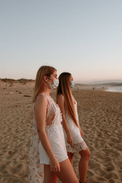 istock Two young women wearing face masks at beach 1239558918