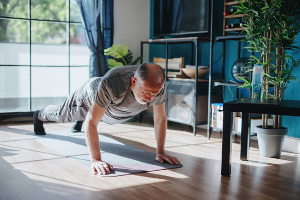 istock Senior man working out at home, plank position 1239569616