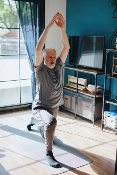 istock Active senior man practicing yoga at home 1239570684