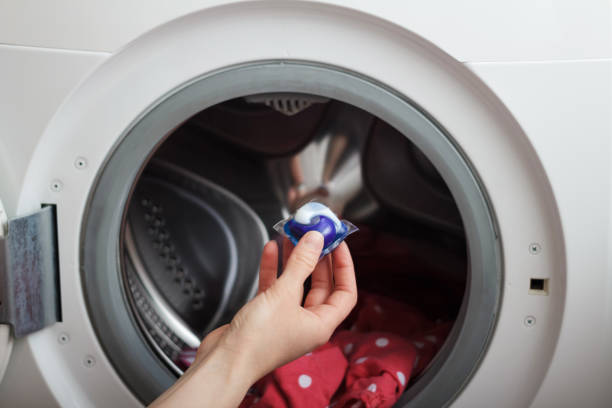 Woman putting detergent pod in washing machine with laundry, closeup Woman putting detergent pod in washing machine with laundry, close-up detergent capsule stock pictures, royalty-free photos & images