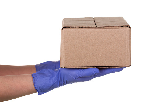 Closeup delivery man hand in medical gloves holding cardboard box isolated on white background, Packaging mockup, Delivery service concept.