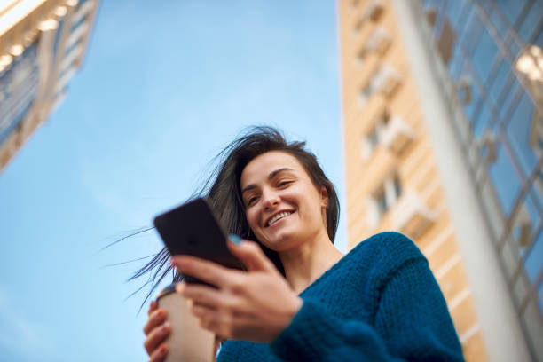 istock Smiling woman with smartphone is surrounded by tall buildings 1239593265