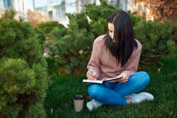 istock Serious young woman taking notes in pocket book at park 1239593283