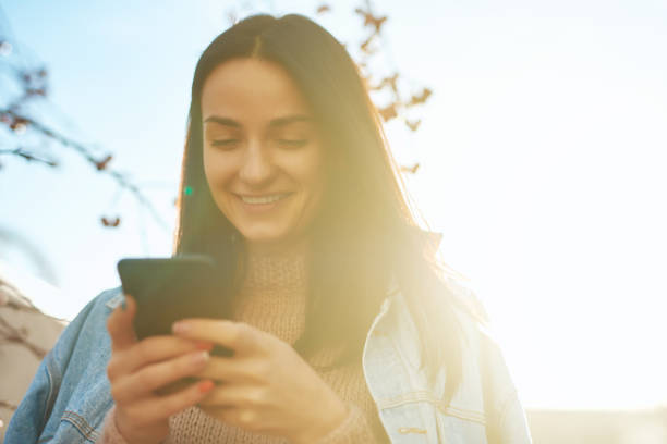 istock Happy lady texting by her smartphone in a beautiful sunlight 1239594409