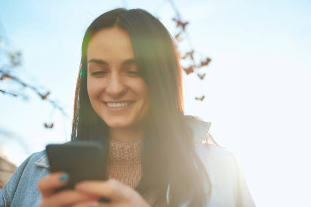 istock Smiling lady making call by her smartphone outdoors 1239594412